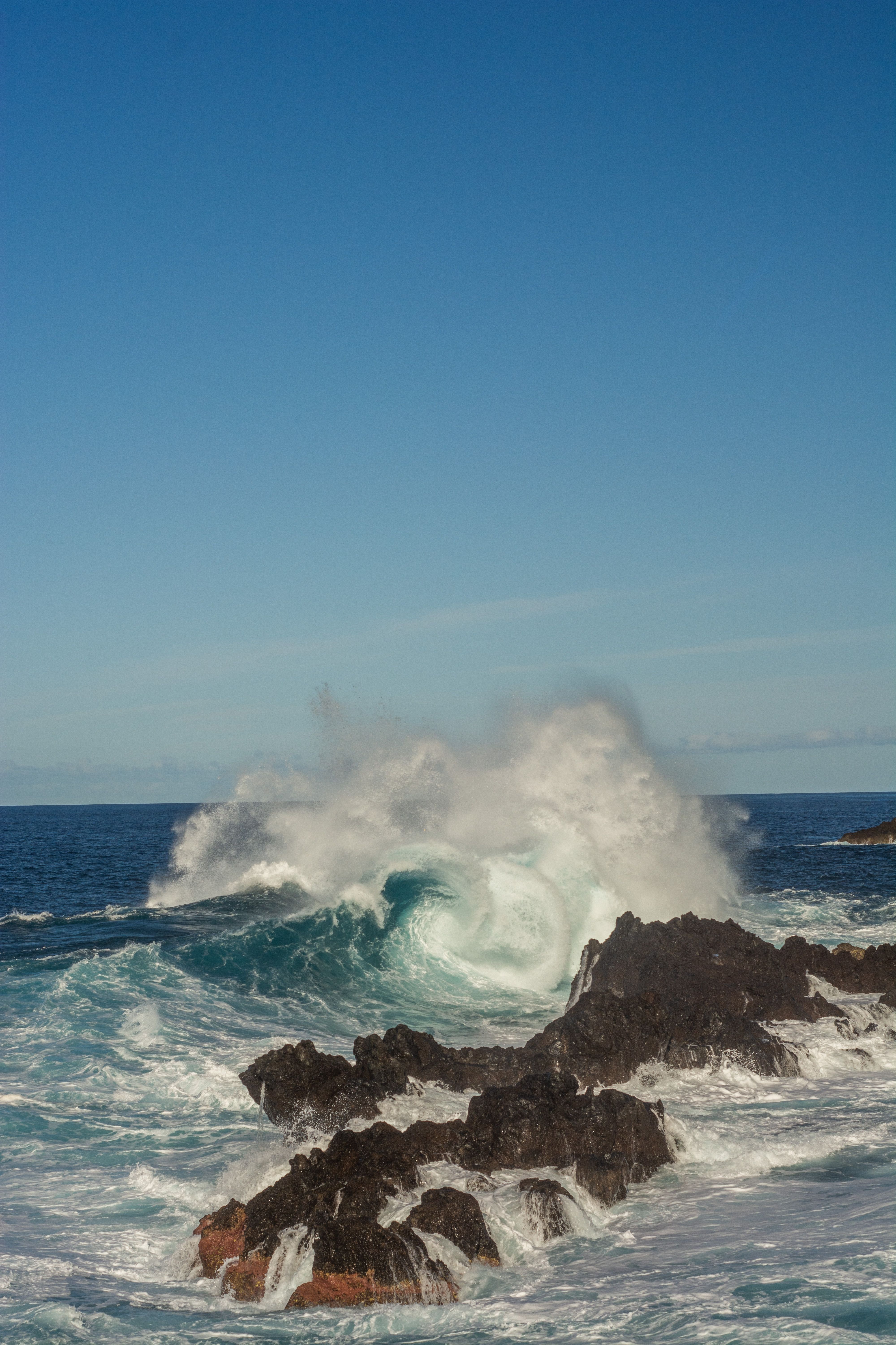 A wave frozen in time breaks over rocks