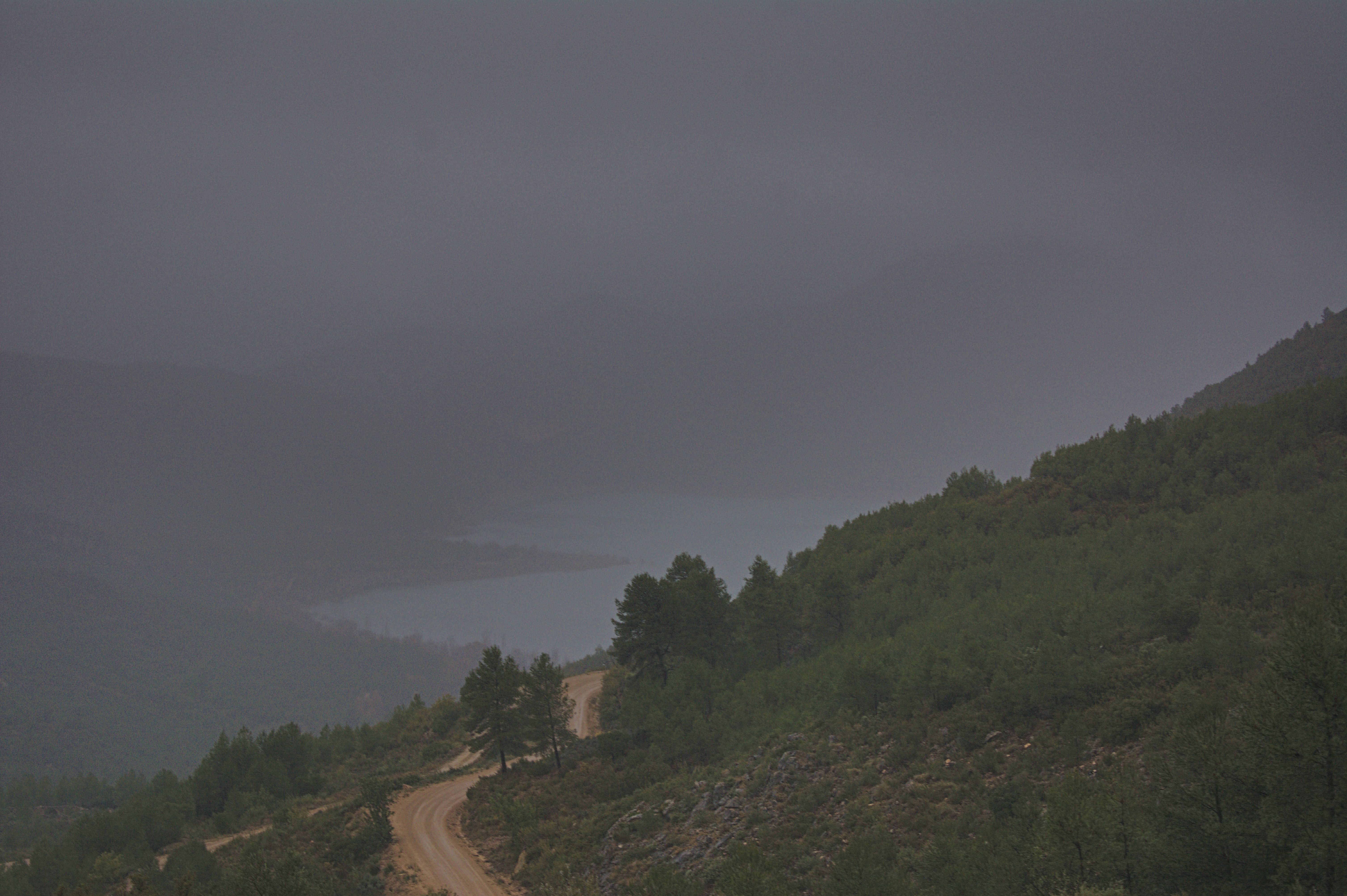 Side of a mountain with a single road, large lake in the distance