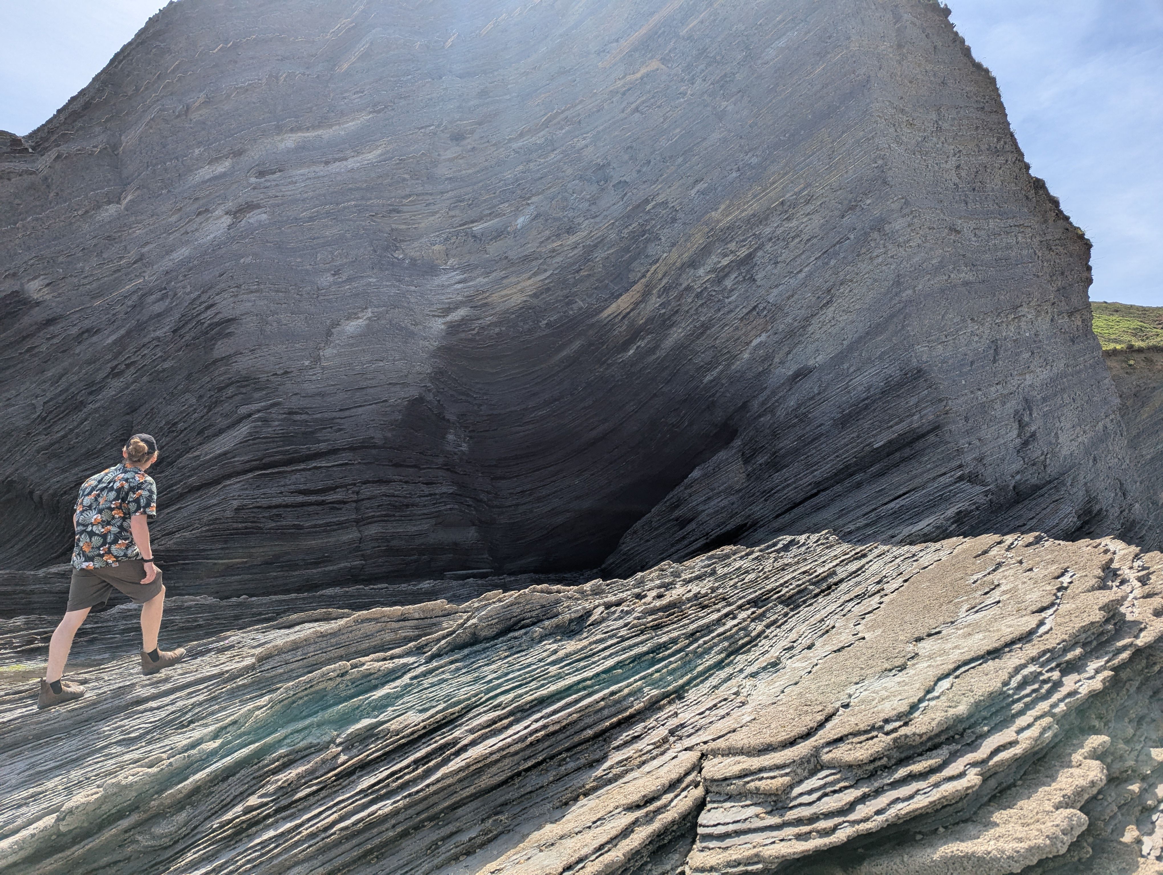 Person auf flysch gestein vor einer Höhle am Meer
