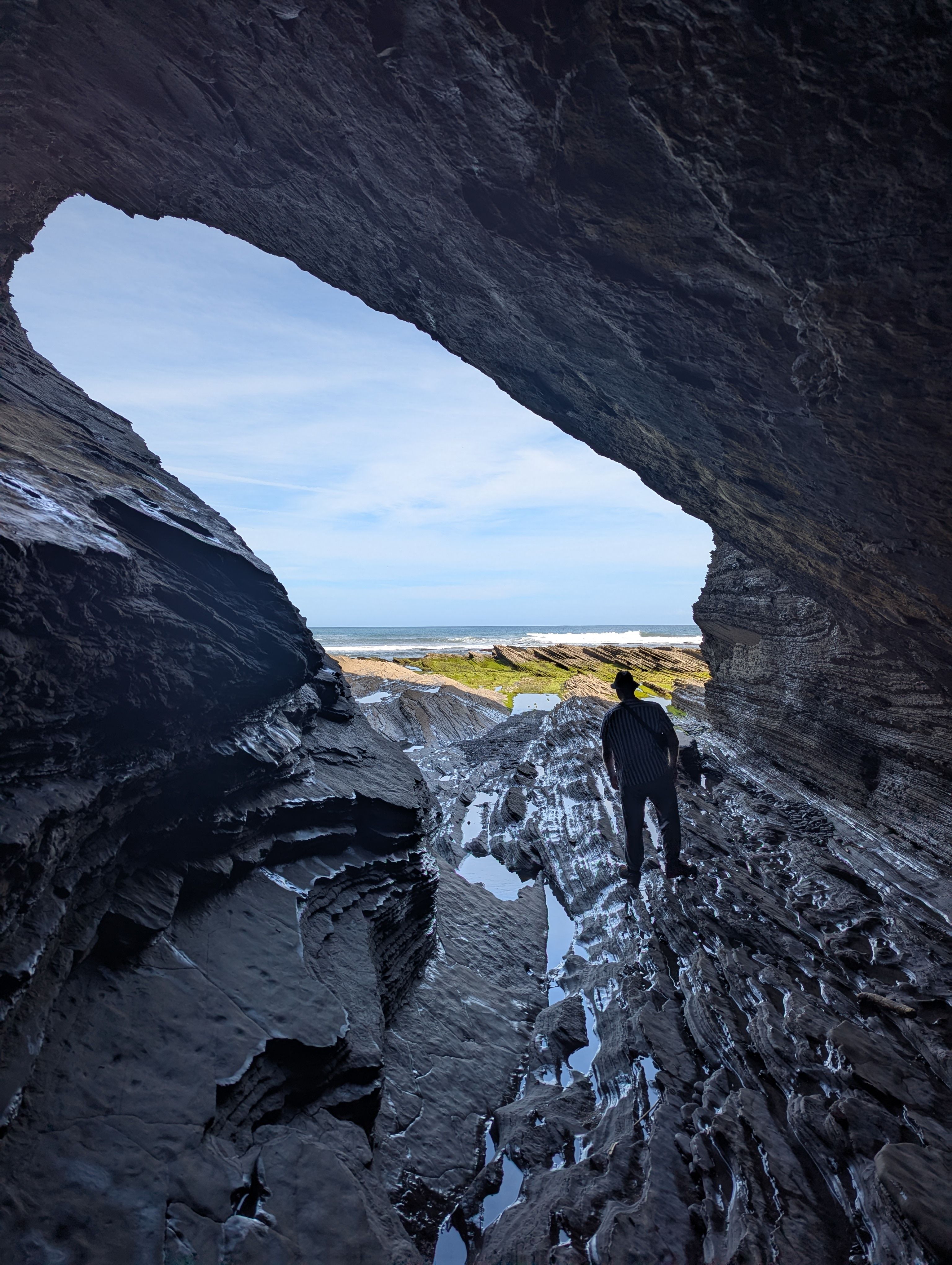 Bild von Person in einer Höhle aus der man das Meer sieht